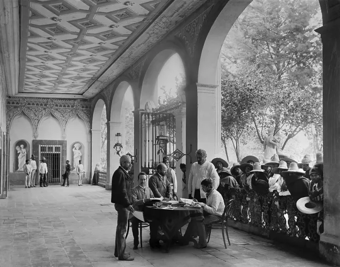 Framed Print : European-Mexican administrator sits in a Hacienda porch, San Luis Potosi, Mexico, c. 1890. Landless mestizo peons wait their turn for an audience with the plantation manager