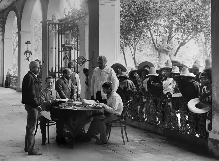 Framed Print : European-Mexican administrator sits in a Hacienda porch, San Luis Potosi, Mexico, c. 1890. Landless mestizo peons wait their turn for an audience with the plantation manager