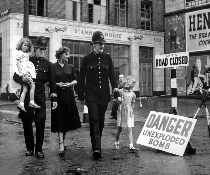 Framed Print : A family is escorted away from the site of an unexploded German bomb in 1948. A 2, 500 pound German bomb, buried opposite University College Hospital, London, fell in 1941