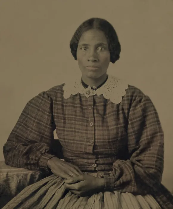 Framed Print : Fashionable dressed, pretty, African American woman of the 1860s. The ambrotype show her gracefully posed, wearing a plaid dress with full long sleeves and a lace collar