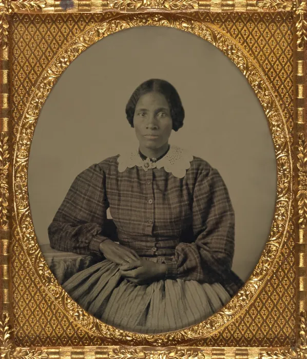 Framed Print : Fashionable dressed, pretty, young, African American woman of the 1860s. The ambrotype show her gracefully posed, wearing a plaid dress with full long sleeves and a lace collar Framed Print : Fashionable dressed, pretty, young, African American woman of the 1860s. The ambrotype show her gracefully posed, wearing a plaid dress with full long sleeves and a lace collar