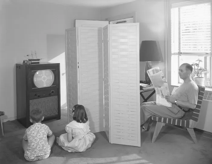 Framed Print : Father reading newspaper, while two children anticipate the start of television programming