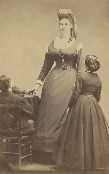 Framed Print : Female giant, Anna Haining, (aka Anna Swan), 7 feet, 11 inches tall, poses with two normal sized people, ca. 1865-70