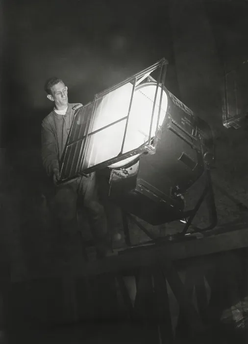 Framed Print : Film engineer using the Dunning Method. He places blue light filter on a special light which will illuminate the filming background