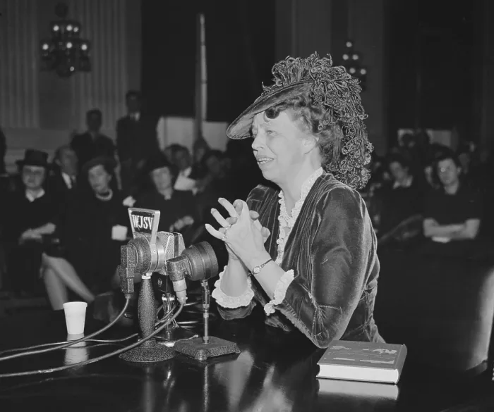 Framed Print : First Lady Eleanor Roosevelt speaking and wearing an adventurous ostrich feathered hat. 1930s. A book, The Way to Democracy, is beside her (BSLOC_2016_10_211)