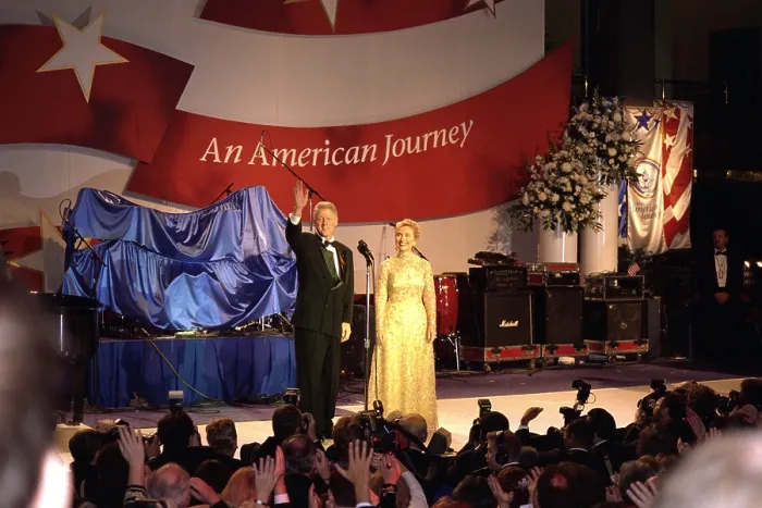 Framed Print : First Lady Hillary Clinton wearing an Oscar de la Renta evening gown at a 1997 Inaugural Ball. President Bill Clinton waves to the crowd beyond the press photographers. Jan