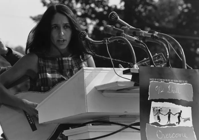 Framed Print : Folk Singer Joan Baez singing at the 1963 Civil Rights March on Washington. A sign hanging near the microphones reads We Shall Overcome. Aug. 28, 1963