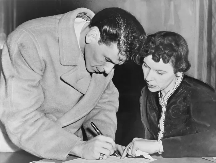 Framed Print : Frank Sinatra (1915-1998), signs his induction papers while Chief Clerk Mrs. Mae E. Jones helps out at local board No. 19-160 in Jersey City