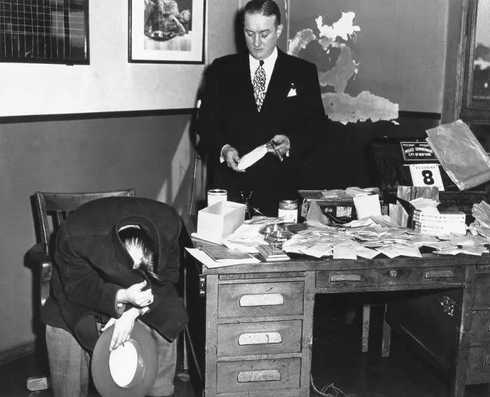 Framed Print : Gangster Joseph Basile, hiding his face with his coat, as photographers take his picture. He was arrested in the seizure of $3 million worth of Narcotics