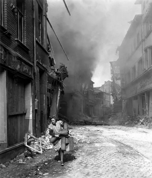 Framed Print : German woman runs from burning building carrying a suitcase and a few rugs. The fire was started in by Nazi saboteur in Seigburg, Germany, during the last month of World War 2