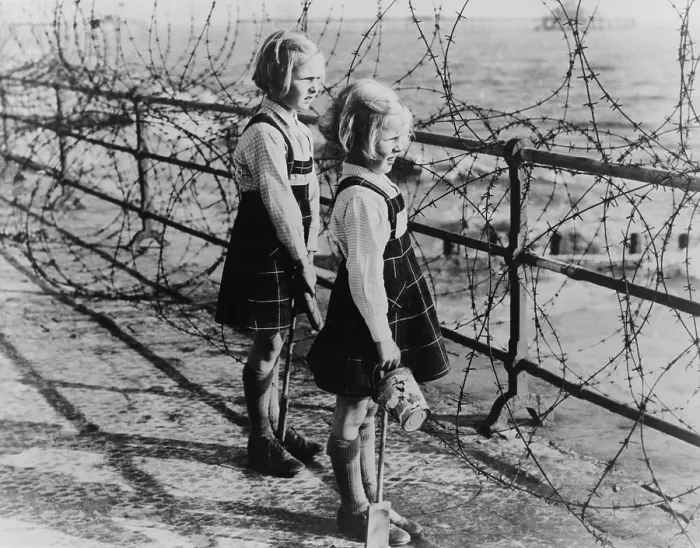 Framed Print : Two girls on the south coast of England look out to the beach through a barbed wire fence in 1940