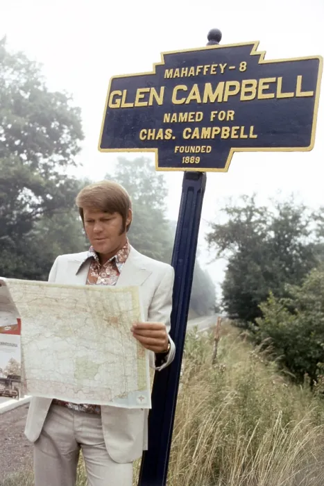 Framed Print : Glen Campbell, posing at the highway marker for the town of Glen Campbell, Pennsylvania, 1971