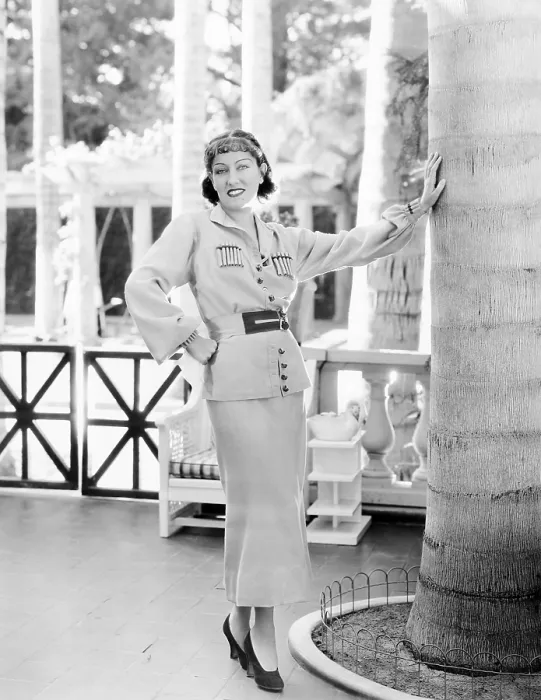 Framed Print : Gloria Swanson, modeling a gold wool sports suit with red trim, ca. 1934