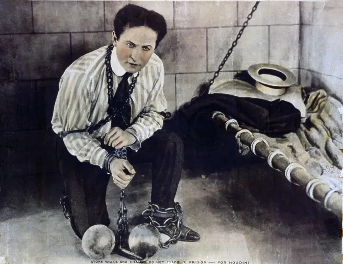 Framed Print : Harry Houdini (1874-1926), in still from a movie he made with Famous Players-Lasky Corporation, shows him chained in a prison cell, from which he will escape. Ca. 1915