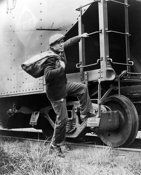 Framed Print : Hobo, Lou Ambers with a large bag over shis shoulder, mounting the ladder of a train car, 1935