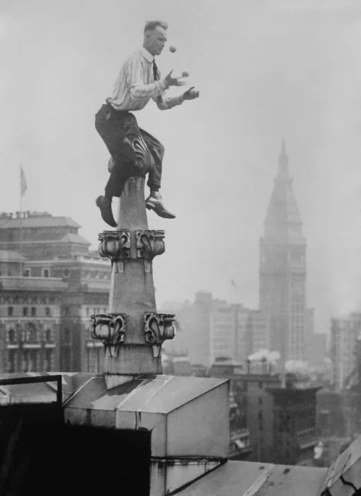 Framed Print : Human Fly John Jammie Reynolds juggles while balancing atop a roof decoration in New York City