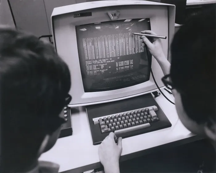 Framed Print : IBM programmers work at a cathode ray monitor with a touch-screen pointer. Ca. 1980 Framed Print : IBM programmers work at a cathode ray monitor with a touch-screen pointer. Ca. 1980