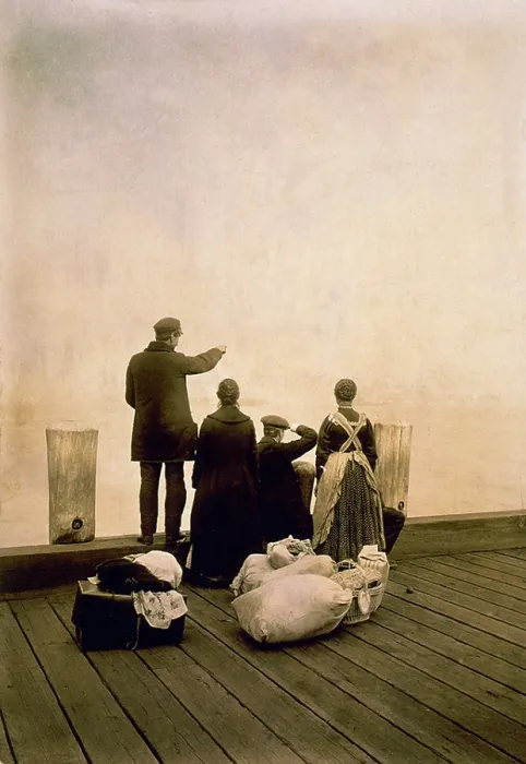 Framed Print : Immigrant family and their belongings on a dock, looking out over the water. Ca. 1912