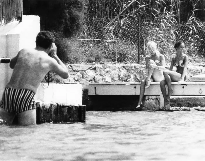Framed Print : An intrusive photographer takes photos of Brigitte Bardot and her companion in St. Tropez, France. Her home on the shore was often approached from the water by paparazzi