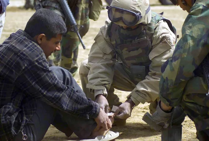 Framed Print : An Iraqi detainee receives a band-aid while under interrogation by a US Marine Corps in Al Shur Iraq during the first week of the Second Gulf War March 24 2003. (BSLOC_2011_12_76)