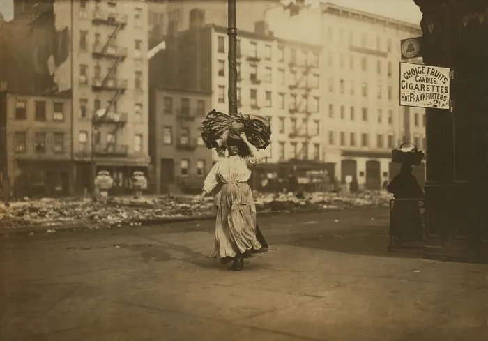 Framed Print : Italian woman carrying heavy bundle of clothing on her head Near Astor Place, New York City. She will sew the garments at home for low wages