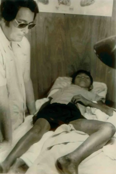 Framed Print : Jim Jones standing over a Guyanese boy with a near-fatal snake bite. He was in the Jonestown clinic and then airlifted to Georgetown. People's Temple Agricultural Project
