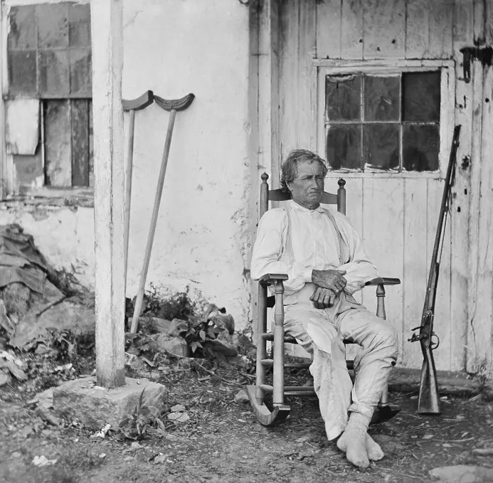 Framed Print : John L. Burns, the old hero of Gettysburg, sits in a rocking chair with his gun and crutches nearby Framed Print : John L. Burns, the old hero of Gettysburg, sits in a rocking chair with his gun and crutches nearby