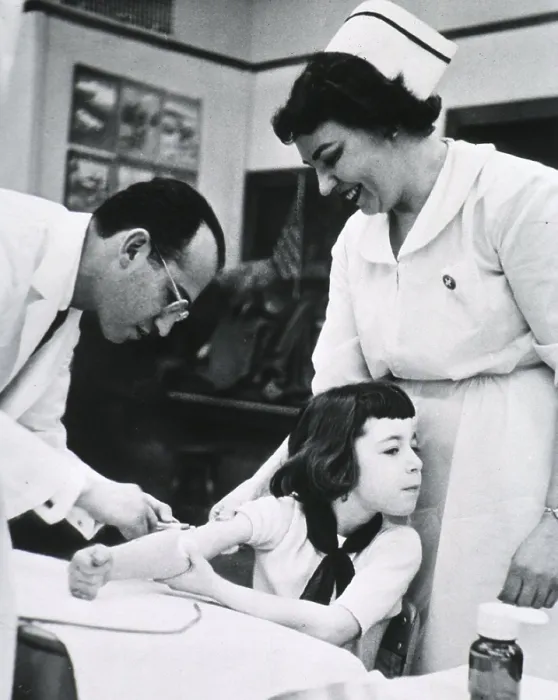 Framed Print : Jonas E. Salk (1914-1995), American physician who developed the first effective Polio vaccine inoculating child as nurse stands by. Ca. 1955