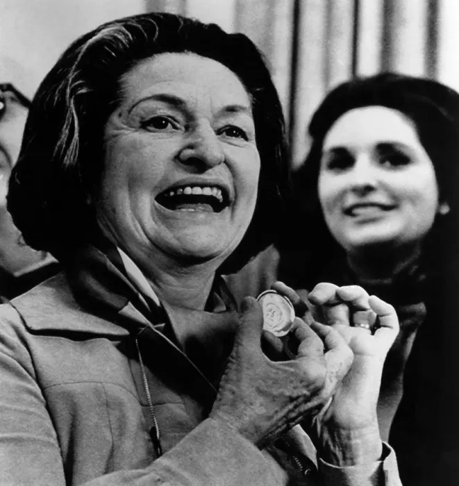 Framed Print : Lady Bird Johnson displaying an 18 karat gold medal honoring her husband, the late president Lyndon Johnson at a presentation, with daughter Lynda in the background