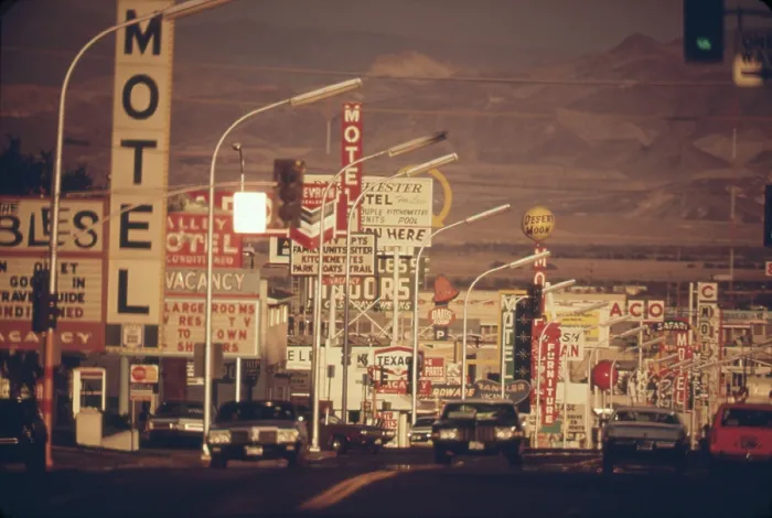 Framed Print : Las Vegas commercial street is a landscape of signs the a desert and mountain backdrop. Ca. 1972-75