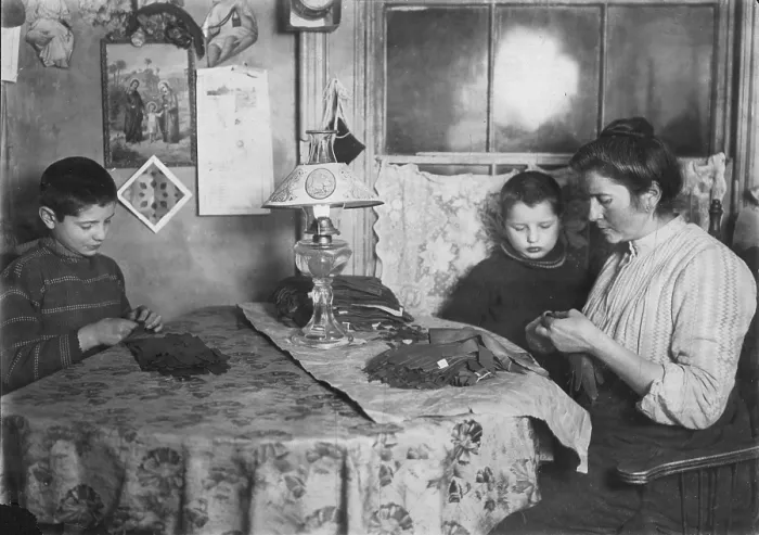 Framed Print : Late at night, sewing tapes on gloves. The boy helps. Family of five sleep in room where the work is done, New York, photograph by Lewis Wickes Hine, February 1908