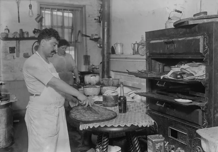 Framed Print : Lebanese-Syrian immigrant pastry cook cutting into a phyllo dough sweet made in the rustic kitchen of in a New York City ethnic restaurant. Ca. 1910