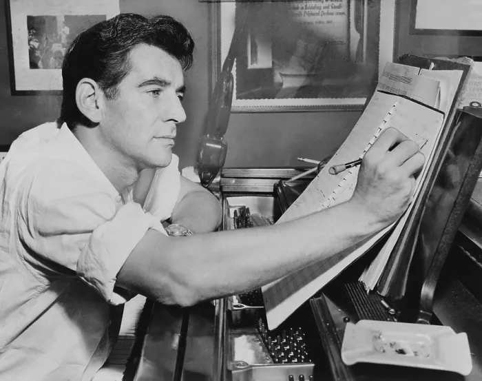 Framed Print : Leonard Bernstein (1918-1990), seated at piano, making annotations to musical score IN 1955