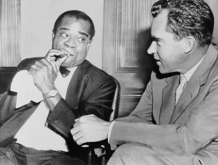 Framed Print : Louis Armstrong (1901-1971) holding horn mouthpiece, demonstrating how to 'make the horn cry' for Vice President Richard Nixon. 1957
