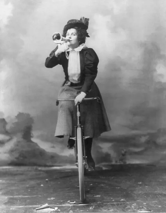 Framed Print : Madge Lessing (1866-1932), English actress and singer, riding bicycle, and holding musical horn to lips. 1898