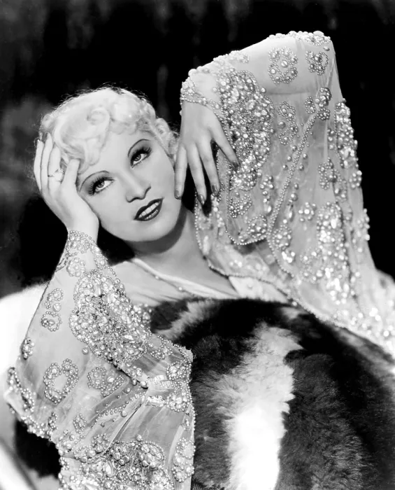 Framed Print : Mae West, in beaded dress, on fur rug, 1930s