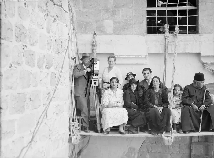Framed Print : Man with movie camera on platform suspended from building, with other people, photograph, 1925-1946