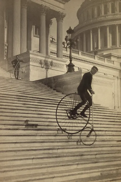 Framed Print : Man riding a penny-farthing bicycle down the Capitol steps in 1884. Another bicyclist stands further up the steps. Photo by the Platt Brothers (BSLOC_2018_2_173)