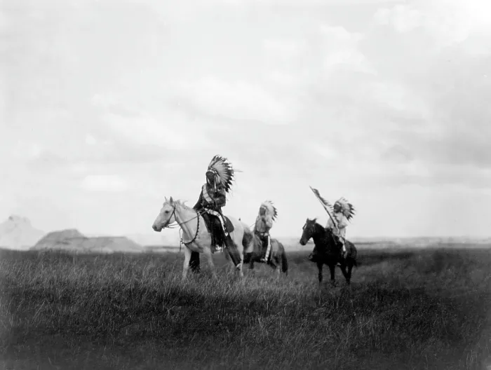 Framed Print : The March of the Sioux, three Sioux Indians on horseback on plains with rock formations in background, photograph by Edward S. Curtis, 1905