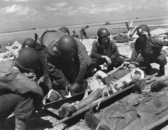 Framed Print : Marine on the stretcher at a dressing station on Tarawa smokes as he is attended by medics. He has a wounded arm and leg. Nov. 20-23, 1943 during World War 2. (BSLOC_2013_14_254)