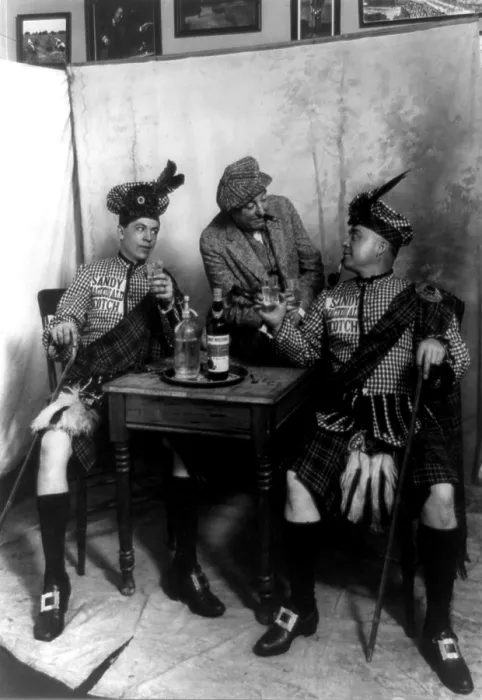 Framed Print : Two men wearing kilts seated at small table, drinking Sandy MacDonald scotch, with man standing and leaning against the table, photograph, 1913 Framed Print : Two men wearing kilts seated at small table, drinking Sandy MacDonald scotch, with man standing and leaning against the table, photograph, 1913
