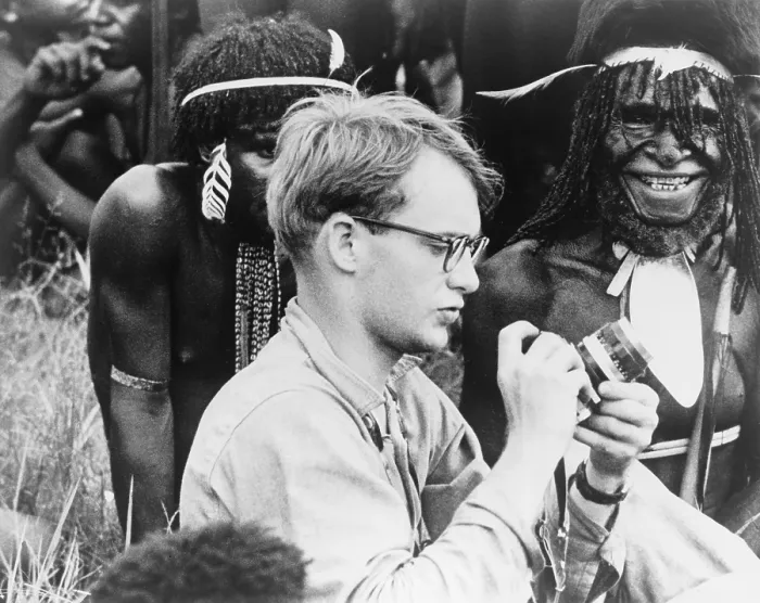 Framed Print : Michael C. Rockefeller (1934-1961) adjusting his camera in New Guinea, Papuan men in background. He disappeared while swimming to shore after a boating accident in New Guinea