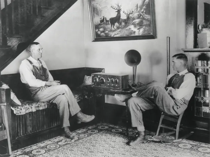 Framed Print : Middle aged farmer and his adult son listening to the radio in their comfortable home, c. 1925