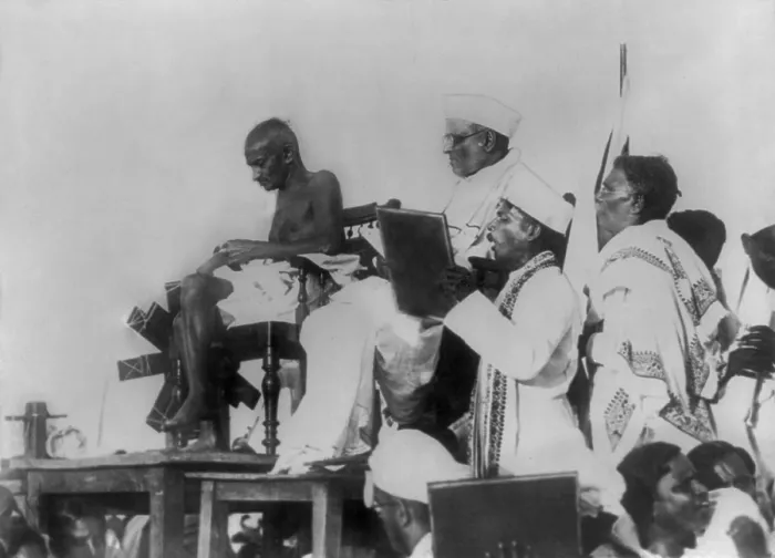 Framed Print : Mohandas Gandhi at the Triplicane Beach meeting in Madras, March 7, 1925. His spinning wheel is beside him as he spins cotton yarn (BSLOC_2020_2_170)