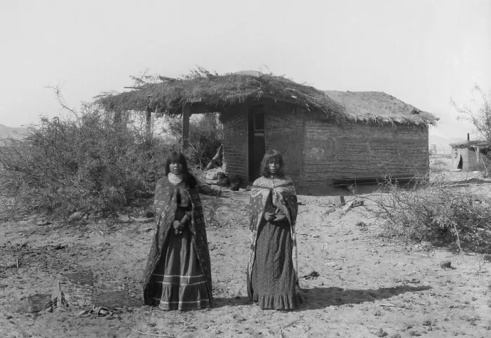 Framed Print : Two Mojave Indians girls stand in front of a small wattle and daub dwelling with a thatched roof, 1900, in this photo by Charles C. Pierce