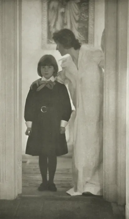 Framed Print : Mother and daughter standing in a doorway, with a picture of the Annunciation on the wall behind them