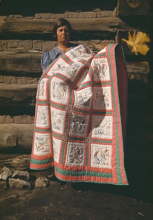 Framed Print : Mrs. Bill Stagg displays her state quilt in front of her log home in Pie Town New Mexico. The quilt had embroidered panes of each of the 48 US States. Oct. 1940