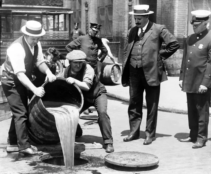 Framed Print : New York City Deputy Police Commissioner John A. Leach, right, watching agents pour liquor down a manhole following a raid during prohibition 1921