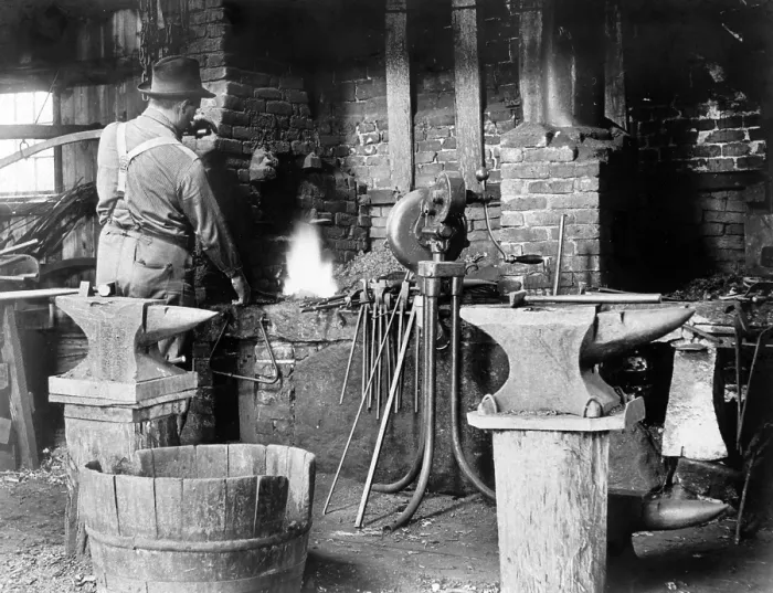 Framed Print : Occupational portrait of a blacksmith, in his smithy with anvils, ca. 1906