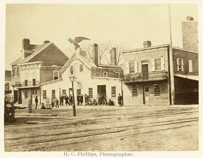Framed Print : Philadelphia in the 1860s. Street scene with men gathered at the giant eagle adorned Union Volunteer Refreshment Saloon next to the Union Volunteer Hospital